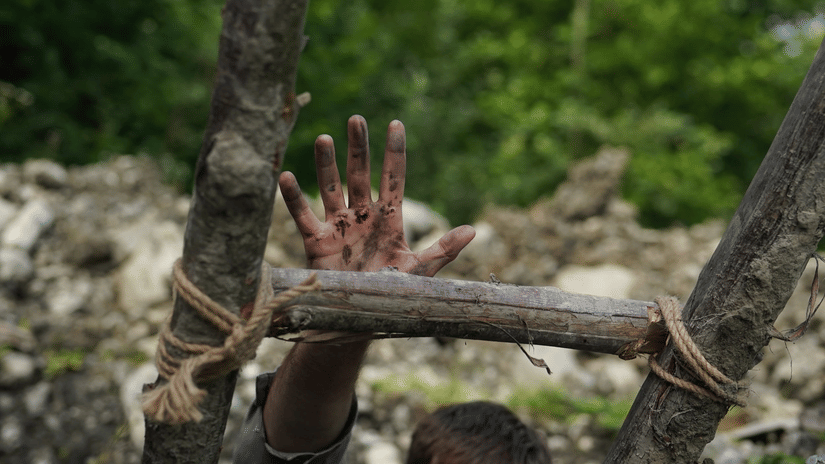 Close-up of hands gripping rough wooden rungs of a ladder, suggesting someone is climbing or descending