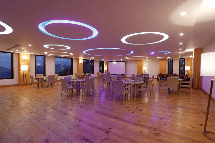  A spacious, elegantly lit hotel banquet hall or restaurant interior at Digantaa Resort in Mukteshwar many tables and chairs, ready for an event