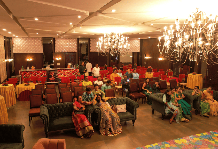 Elegant indoor reception shows guests comfortably seated at tables beneath warm chandeliers and soft lighting at Digantaa Resorts in Mukteshwar